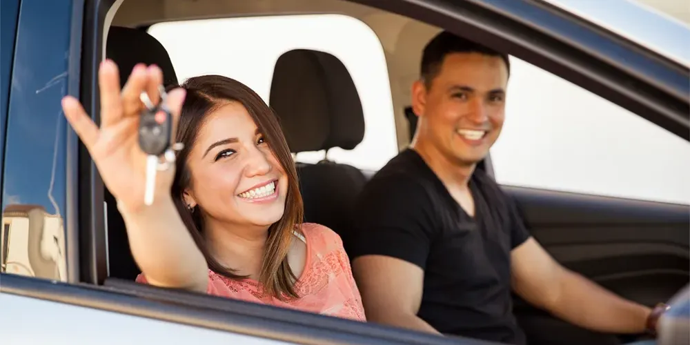 Couple driving home happy with car keys in woman's hand