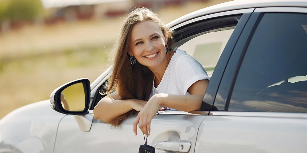 happy couple holding keys in front of their new used car