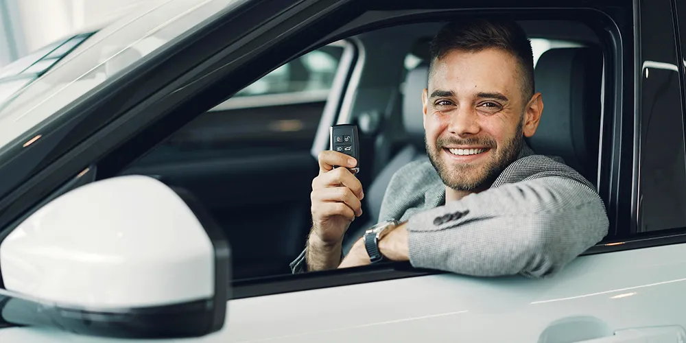 happy couple holding keys in front of their new used car