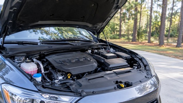 Illustration for used car recalls in Conroe TX: open hood and engine bay of a clean used car in a driveway